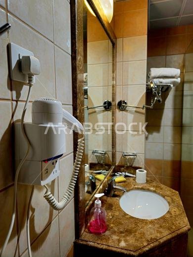 Medina, Saudi Arabia, June 26 2024: a shower cabin stall with a glass barrier, bathroom basin, toilet seat and hair dryer, in a hotel in Madinah city Medina, Saudi Arabia, June 26 2024: a shower cabin stall with a glass barrier, bathroom basin, toilet seat and hair dryer, in a hotel in Madinah city