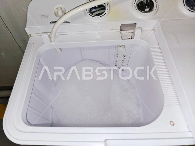 Mecca, Saudi Arabia, June 22 2024: manual top load washing machine, laundry clothes washer, a home appliance used to wash laundry, user adds laundry d