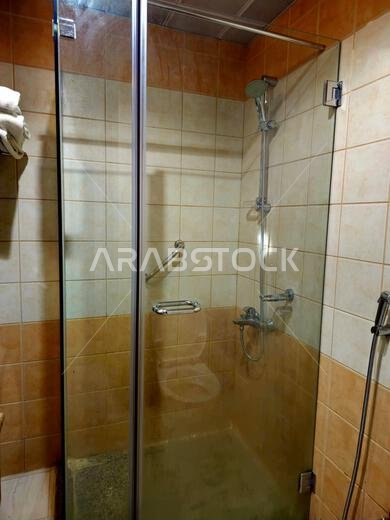 shower is a place in which a person bathes under a spray of typically warm or hot water, with a drain in the floor, a shower cabin stall with a glass