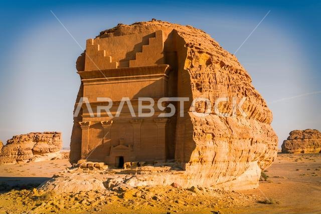 مقبرة أسد الكوزة عند غروب الشمس، نصب تذكاري من الحجر الرملي المنحوت على الطراز النبطي في مدينة الحِجر القديمة، إحدى عجائب الآثار في العلا، المملكة العربية السعودية مقبرة أسد الكوزة عند غروب الشمس، نصب تذكاري من الحجر الرملي المنحوت على الطراز النبطي في مدينة الحِجر القديمة، إحدى عجائب الآثار في العلا، المملكة العربية السعودية