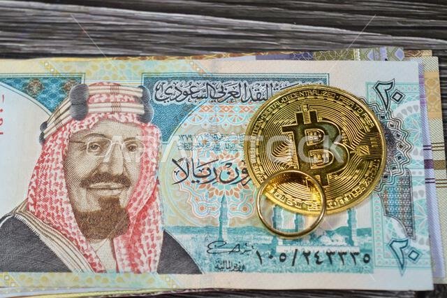 أوراق نقدية سعودية من فئة الريال السعودي، وعملة بيتكوين الذهبية المادية (BTC)، وهي أول عملة مشفرة لامركزية، وخاتم ذهبي. أوراق نقدية سعودية من فئة الريال السعودي، وعملة بيتكوين الذهبية المادية (BTC)، وهي أول عملة مشفرة لامركزية، وخاتم ذهبي.