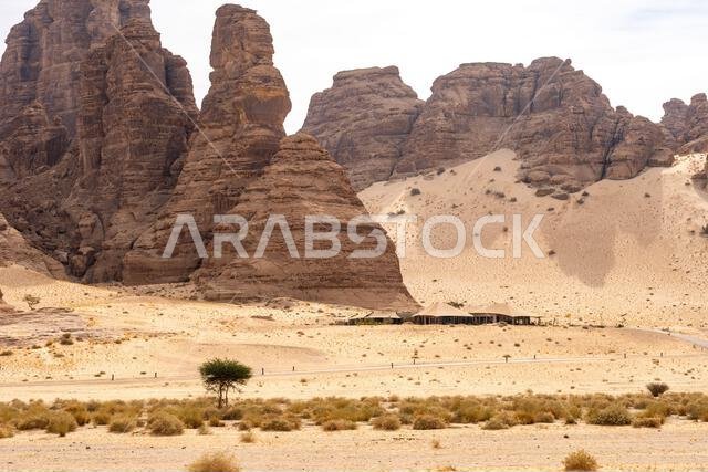 تُشكّل التكوينات الرملية في وادي آشر خلفيةً خلابةً للمنتجعات الفاخرة ضمن المناظر الصحراوية المذهلة في العلا، المملكة العربية السعودية.