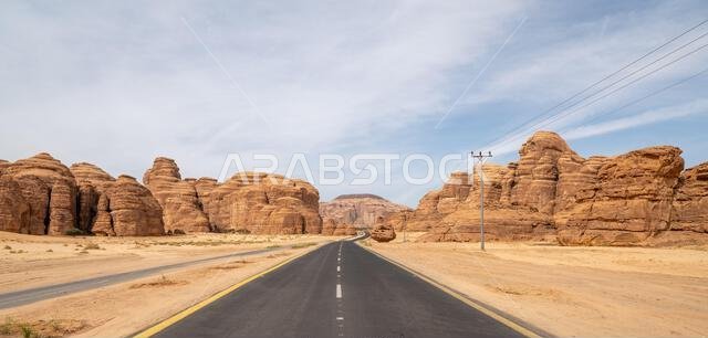 يُبرز الطريق الصحراوي الخلاب بين العلا وتبوك في المملكة العربية السعودية تكوينات صخرية رملية مذهلة وإطلالة بانورامية خلابة.