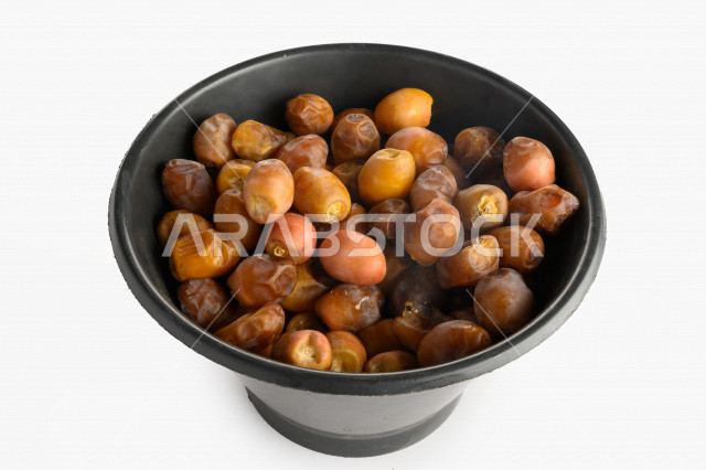 سله سوداء مليئه برطب منيفي من نخيل المملكه العربيه السعوديه, حصاد النخيل في مزارع المملكه, تمر منيفي, رطب نوع فاخر بخلفية بيضاء