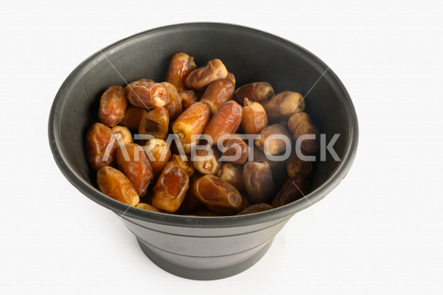 سله سوداء مليئه برطب صقعي من نخيل المملكه العربيه السعوديه, حصاد النخيل في مزارع المملكه, تمر صقعي, رطب نوع فاخر بخلفية بيضاء