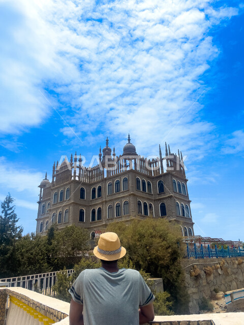 A picture from the back of a tourist enjoying watching the heritage headquarters palace in the tourist village of Al-Maqar in the city of Al-Namas in Asir, a heritage tourist village in the Kingdom of Saudi Arabia, the astronomical palace in Saudi Arabia,