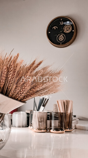 صورة لبيئة عمل ، مكتب عمل ، مجموعة من نباتات القمح ، ساعة رقمية معلقة على الحائط ، ديكور لمكتب عمل ، أدوات وأقلام مكتبية