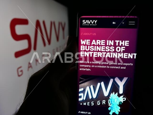 شتوتغارت، ألمانيا - 13-06-2025: شخص يحمل هاتفًا محمولًا يعرض صفحة ويب لشركة ألعاب الفيديو السعودية "سافي جيمز جروب" أمام الشعار.