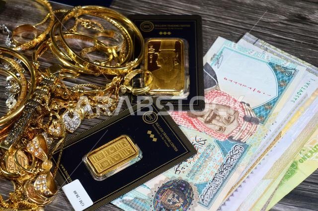 Cairo, Egypt, July 17 2025: Saudi Arabia riyals currency, 24K karat BTC Bullion Trading Center pure yellow gold bars, and Jewellery jewelry stack of g