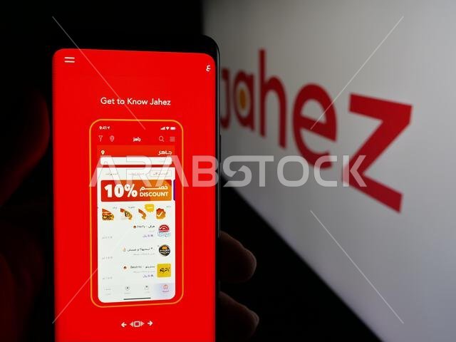 Stuttgart, Germany - 06-13-2025: Person holding smartphone with web page of Saudi Arabian food delivery app company Jahez on screen in front of logo.