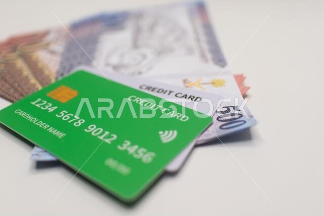 بطاقة ائتمان خضراء على رزمة من الأوراق النقدية بالريال السعودي.