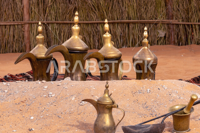 مجموعة من أباريق القهوة العربية الشرقية القديمة مصنوعة من النحاس بأسلوب تقليدي على الرمال ، تراثيات سعودية ، قطع أنتيكة نحاسية ، المملكة العربية السعودية