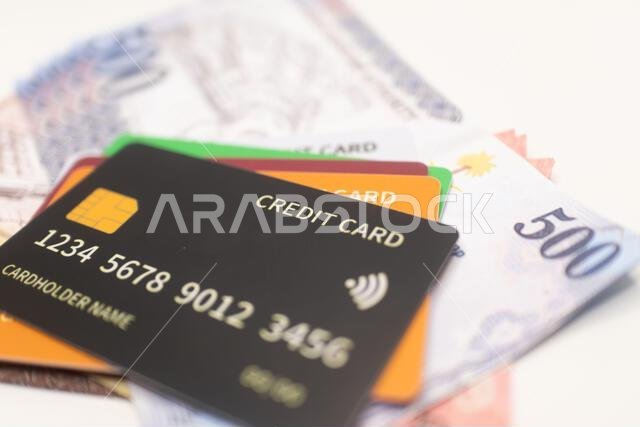 بطاقة ائتمان سوداء على رزمة من الأوراق النقدية بالريال السعودي.