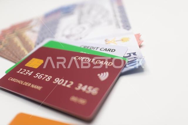 بطاقة ائتمان مارونية اللون على رزمة من الأوراق النقدية بالريال السعودي.