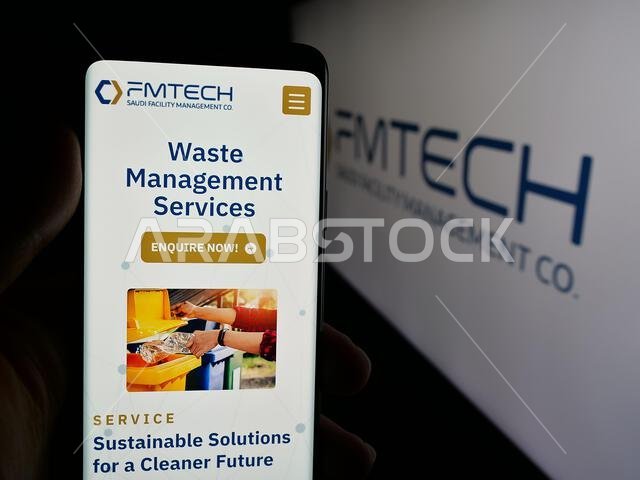 Stuttgart, Germany - 06-14-2025: Person holding smartphone with web page of Saudi Facility Management Company (FMTECH) on screen in front of logo.