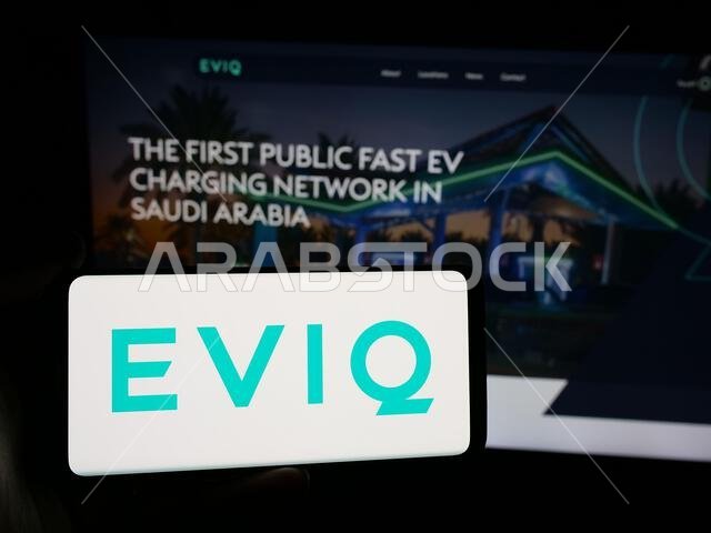 Stuttgart, Germany - 06-14-2025: Person holding smartphone with logo of Electric Vehicle Infrastructure Company EVIQ on screen in front of website. Stuttgart, Germany - 06-14-2025: Person holding smartphone with logo of Electric Vehicle Infrastructure Company EVIQ on screen in front of website.
