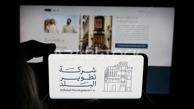 شتوتغارت، ألمانيا - 14-06-2025: شخص يحمل هاتفًا محمولًا عليه شعار شركة البلد للتطوير (BDC) على الشاشة أمام صفحة الويب.