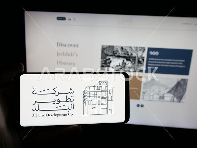 شتوتغارت، ألمانيا - 14-06-2025: شخص يحمل هاتفًا ذكيًا عليه شعار شركة البلد للتطوير (BDC) على الشاشة أمام موقع الويب.