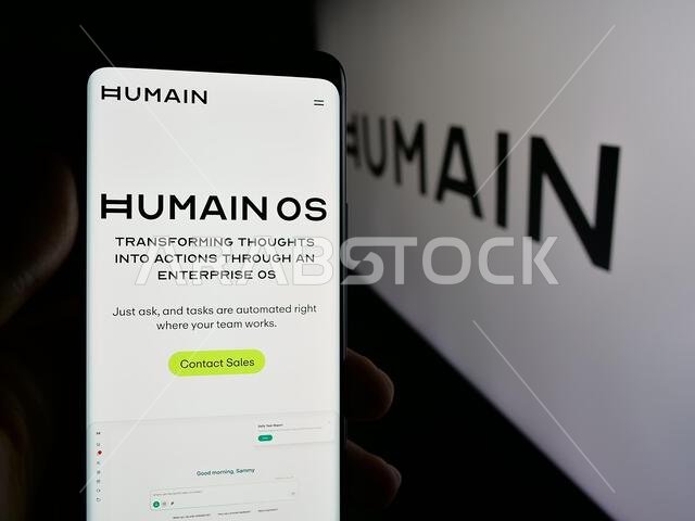 شتوتغارت، ألمانيا - 06-12-2025: شخص يحمل هاتفًا محمولًا يعرض صفحة ويب لشركة الذكاء الاصطناعي السعودية "هيومين" أمام الشعار.