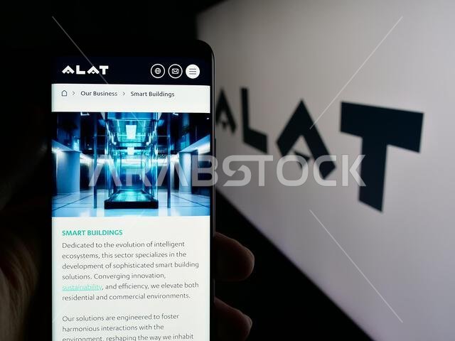 Stuttgart, Germany - 06-12-2025: Person holding cellphone with webpage of Saudi Arabian technology company Alat on screen in front of logo.