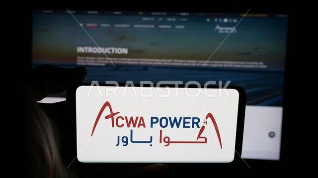 Stuttgart, Germany - 06-12-2025: Person holding cellphone with logo of Saudi energy generation company ACWA Power on screen in front of webpage. Stuttgart, Germany - 06-12-2025: Person holding cellphone with logo of Saudi energy generation company ACWA Power on screen in front of webpage.