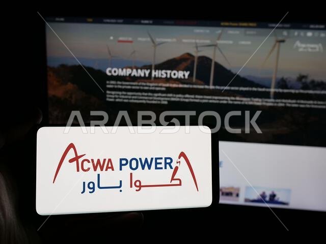 شتوتغارت، ألمانيا - 06-12-2025: شخص يحمل هاتفًا ذكيًا عليه شعار شركة توليد الطاقة السعودية ACWA Power على الشاشة أمام موقع الويب. شتوتغارت، ألمانيا - 06-12-2025: شخص يحمل هاتفًا ذكيًا عليه شعار شركة توليد الطاقة السعودية ACWA Power على الشاشة أمام موقع الويب.
