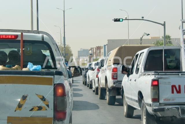 رجل أجنبي يمد يده من السيارة بينما تنتظر السيارات الأخرى إشارة المرور لتفتح في المملكة العربية السعودية