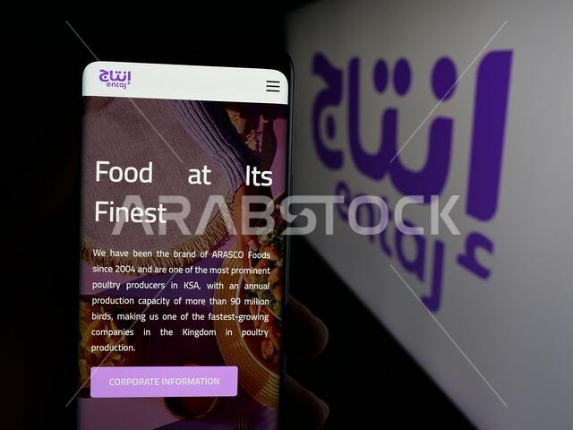 Stuttgart, Germany - 06-13-2025: Person holding cellphone with webpage of Saudi Arabian food company Entaj Foods on screen in front of logo.