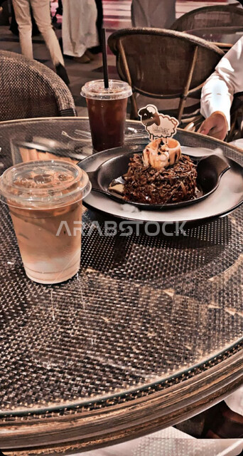 صورة مقربة لأشخاص في جلسة هادئة في مقهى سعودي ، أجواء عيد الأضحى المبارك في أحد مقاهي السعودية ، كافيهات ومطاعم ، صورة لطاولة عليها مشروبات باردة  وطبق من الحلويات الشهية