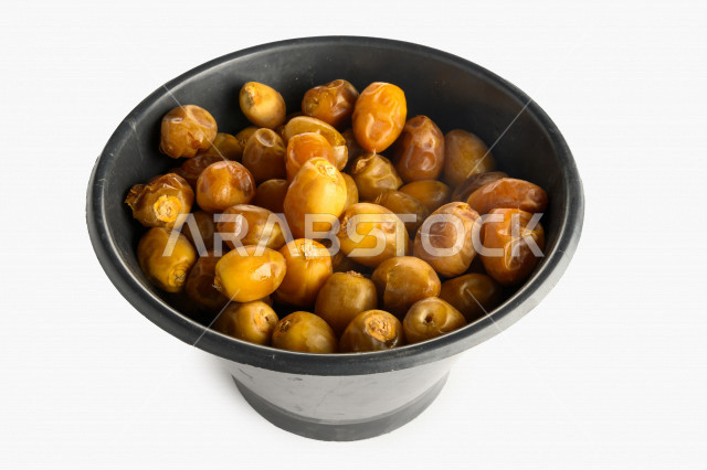 سله سوداء مليئه بالبلح الاصفر من نخيل المملكه العربيه السعوديه, حصاد النخيل في مزارع المملكه, نبوت سيف, رطب نوع فاخر بخلفية بيضاء