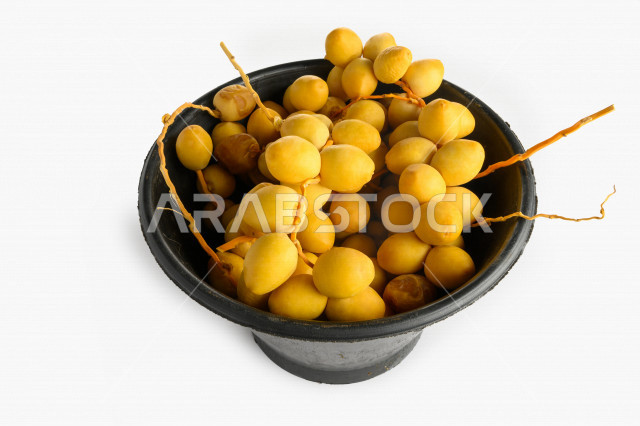 سله سوداء مليئه بالبلح الاصفر من نخيل المملكه العربيه السعوديه, حصاد النخيل في مزارع المملكه, نبوت سيف, رطب نوع فاخر بخلفية بيضاء
