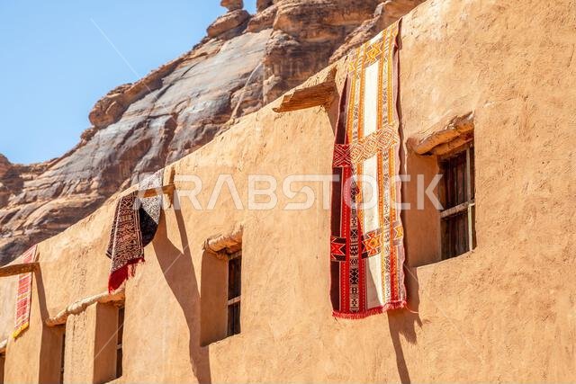 سجاد عربي مزخرف معلق من أسطح المنازل الطينية التقليدية، العلا، منطقة المدينة المنورة، المملكة العربية السعودية
