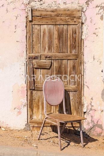 Middle East, Saudi Arabia, Tabuk, Duba. A chair in front of an old wooden door. Middle East, Saudi Arabia, Tabuk, Duba. A chair in front of an old wooden door.