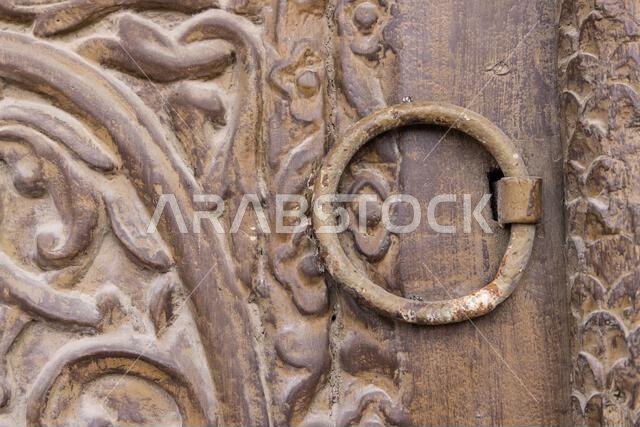 Middle East, Saudi Arabia, Mecca, Jeddah, Al-Balad. Metal pull on a carved wooden door in the Al-Balad historical district.