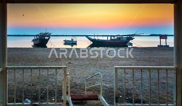 شروق الشمس الذهبي في كورنيش الدمام، المملكة العربية السعودية: مياه هادئة وقوارب تحتضنها أشعة الصباح.