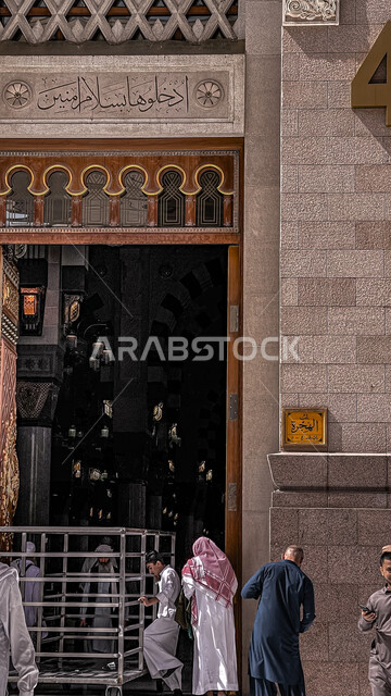 صورة من الخلف لمصلين يدخلون بوابة المسجد النبوي الشريف في المدينة المنورة بالمملكة العربية السعودية، الفن الهندسي المعماري الاسلامي، العبادة والتقرب الى الله ، المسجد النبوي الشريف، اسلاميات وعبادة