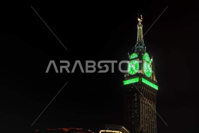 Mecca, Saudi Arabia - March 07, 2023: Green illuminated watch tower of Abraj Al Bait building in Mecca against black night sky. Height 601m it is four