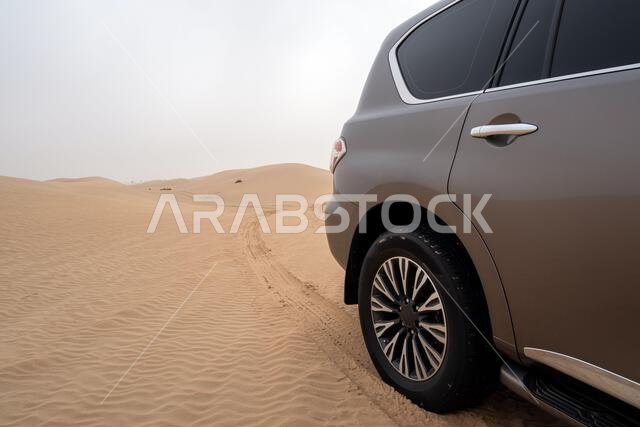 سيارة دفع رباعي في منطقة القدرة، الربع الخالي، صحراء متصلة في دبي، الإمارات العربية المتحدة، الشرق الأوسط، مع مسارات الرياح وكثبان رملية وسماء رمادية ملبدة بالغيوم
