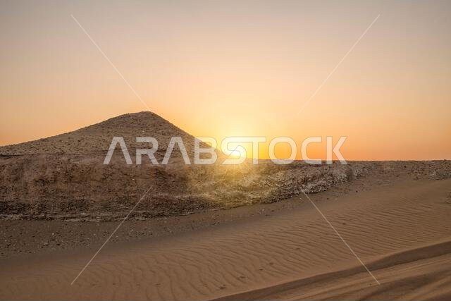 تشرق الشمس في الصحراء. صورة فوتوغرافية لمنظر طبيعي صحراوي عند شروق الشمس وغروبها. شروق الشمس في صحراء الخليج العربي، حيث تظهر الكثبان الرملية ونقوش الرمال بوضوح تحت أشعة الشمس.