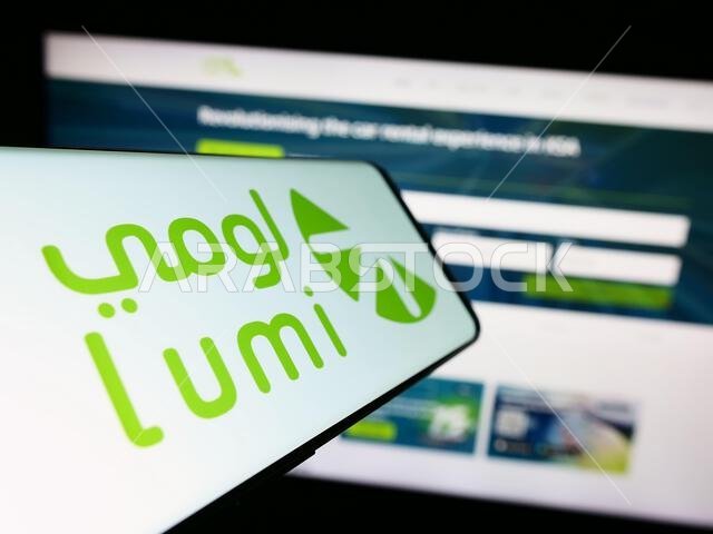 Smartphone with logo of Saudi Arabian car rental company Lumi on screen in front of business website. Focus on center of phone display.