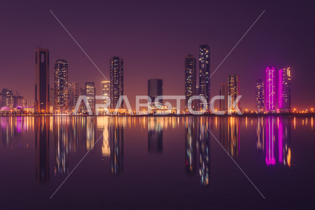 An aesthetic image of the reflection of towers and skyscrapers on the water in Sharjah, United Arab Emirates, illuminated towers and skyscrapers at night, tourism in the Emirates.