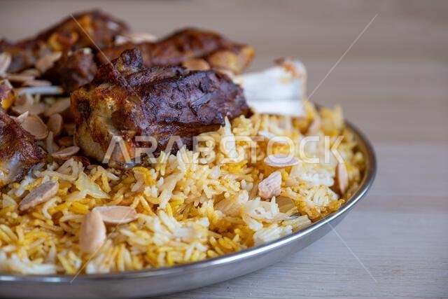 Plate of meat and rice topped with almonds on wooden table with top view Plate of meat and rice topped with almonds on wooden table with top view