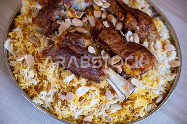 Plate of meat and rice topped with almonds on wooden table with top view