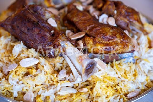Plate of meat and rice topped with almonds on wooden table with top view
