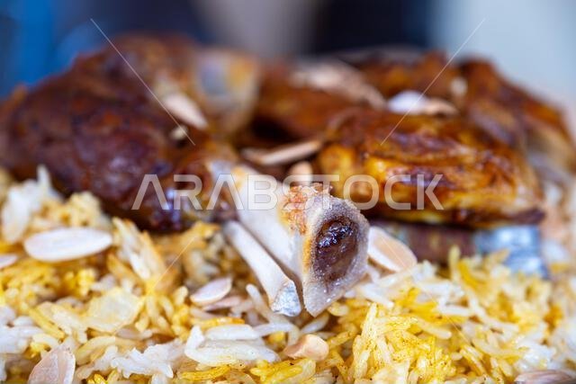 Plate of meat and rice topped with almonds on wooden table with top view