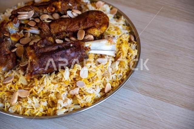 Plate of meat and rice topped with almonds on wooden table with top view