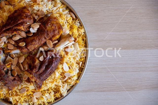 طبق من اللحم والأرز مغطى باللوز على طاولة خشبية مع منظر علوي