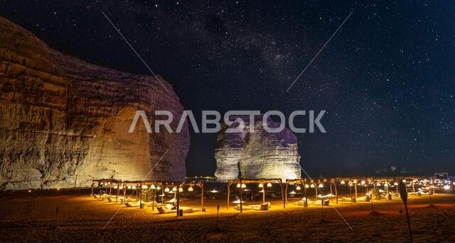 Illuminated outdoor lounge in front of elephant rock erosion monolith standing in the night starlight desert, Al Ula, Saudi Arabia