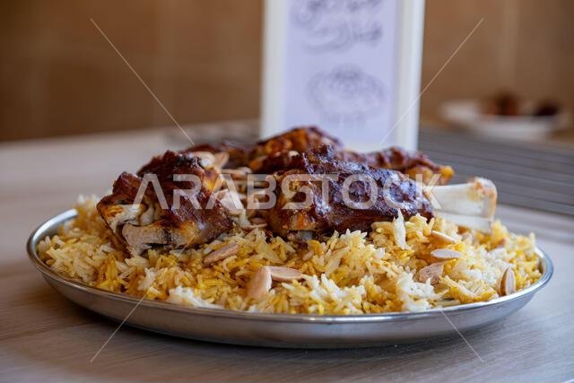 طبق من اللحم والأرز مغطى باللوز على طاولة خشبية لعيد الأضحى المبارك.