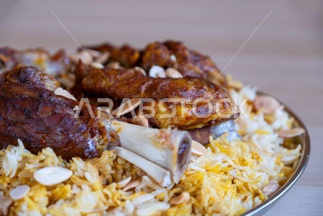 Plate of meat and rice topped with almonds on wooden table with top view